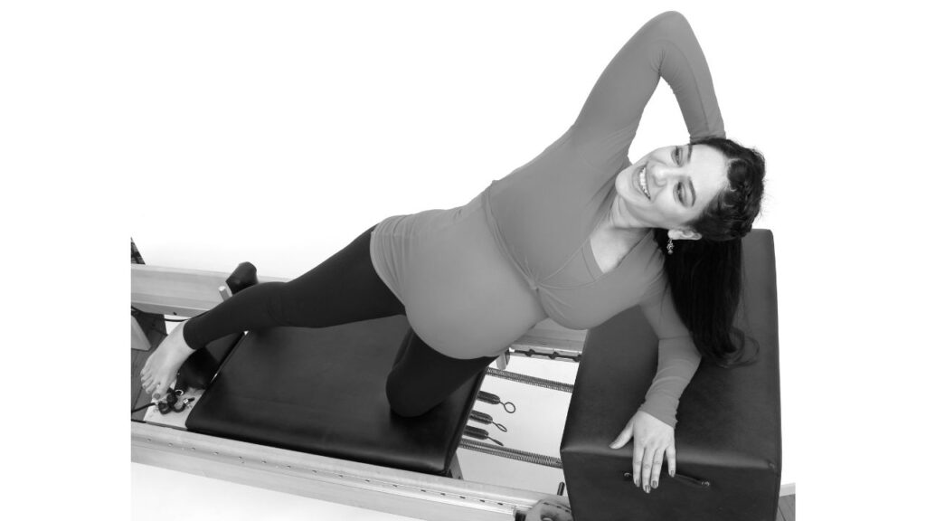 Pregnant woman on the Pilates Reformer doing a modified side plank